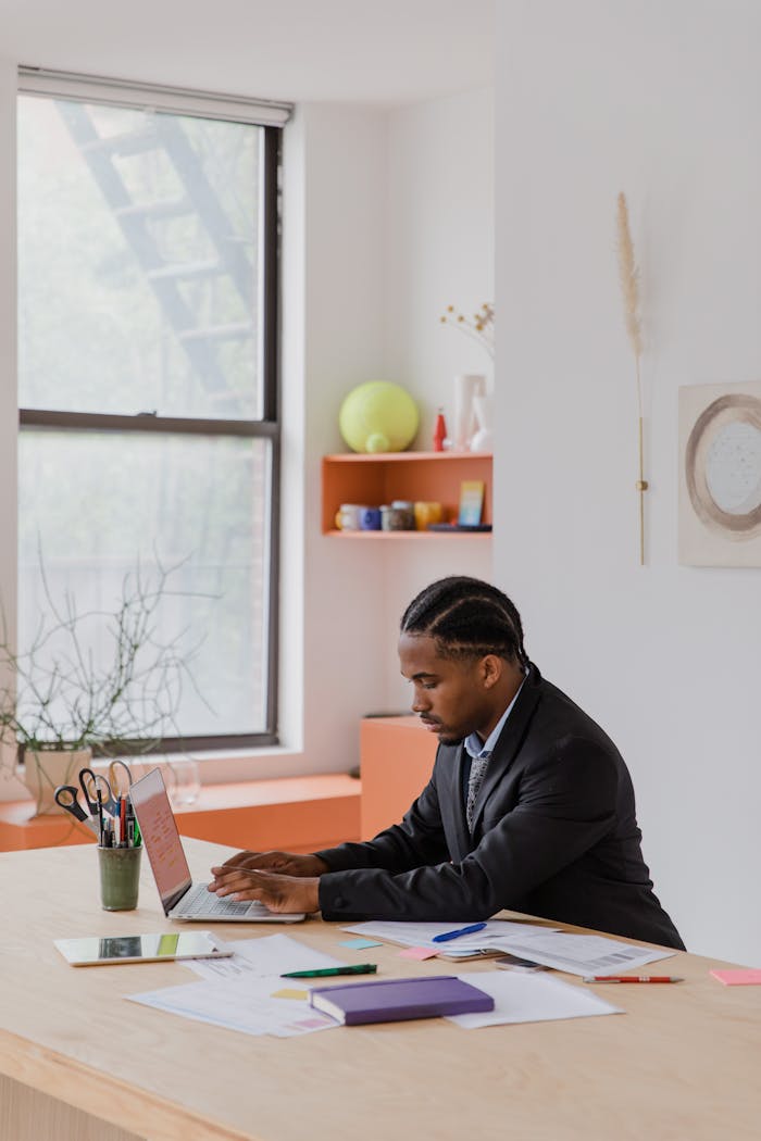 Professional man working on a laptop in a well-designed modern office space.